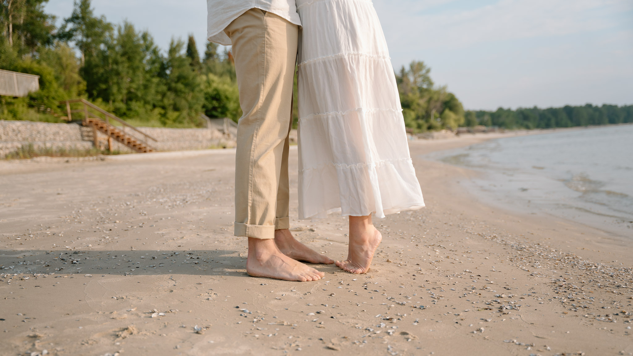 Lester Beach Manitoba engagement photos barefoot couple standing on shoreline Lake Winnipeg