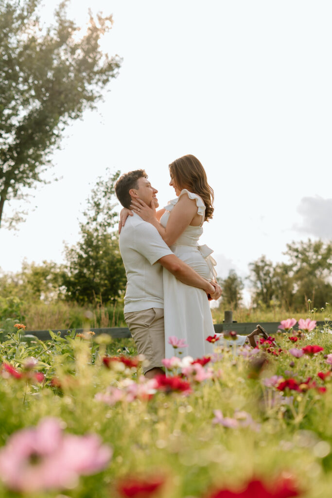 Couple embracing in flower field during Miss Millie’s Flower Farm engagement session in Manitoba with warm summer sunlight.