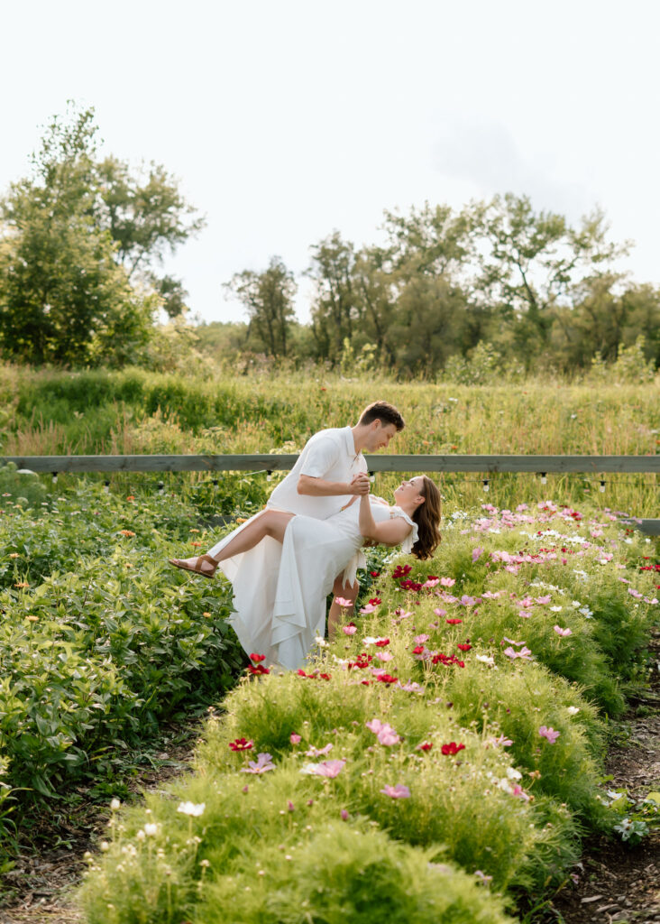 Couple dipping in flower garden during Miss Millie’s Flower Farm engagement session in Manitoba.