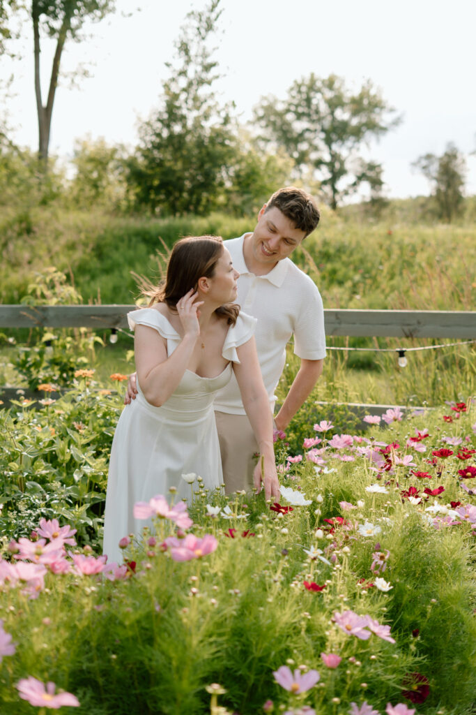 Couple standing among flowers during Miss Millie’s Flower Farm engagement session in Manitoba with summer blooms.