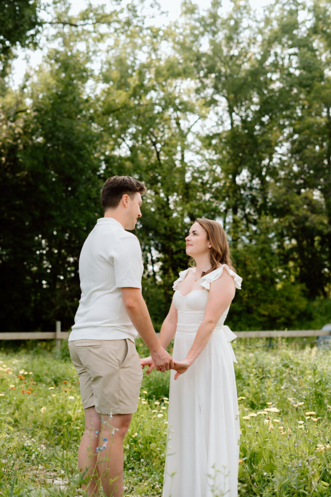 Couple holding hands in wildflower field during Miss Millie’s Flower Farm engagement session in Manitoba.